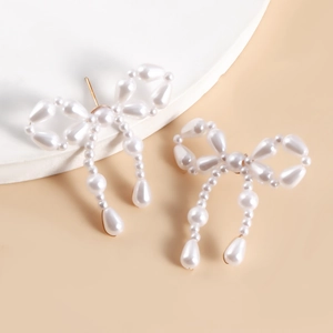 Detailed view of handmade bow earrings crafted from lustrous faux pearls and drop pendants