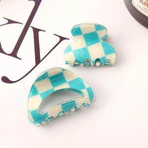 Detail shot of two blue and beige checkered hair claws on a clean aesthetic background