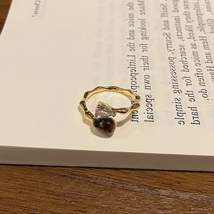 Detail of 18k gold tiger eye ring on vintage book with warm wood background aesthetics
