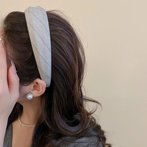 Detail of grey herringbone fabric headband styled with elegant pearl accessories on model