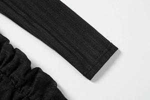 Detail of black ribbed knit fabric featuring side ruched texture and tight cuff stitching