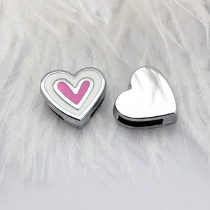 Close-up of pink and white enamel heart charms on elegant white feathers background