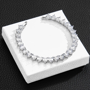 Macro shot of silver heart-shaped tennis chain with zircons on a white jewelry box