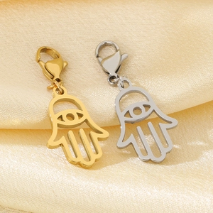 Détail des pendentifs main de fatma en or et argent sur un tissu en soie