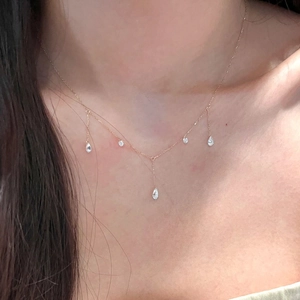 Detail shot of a gold tassel Y-necklace with waterdrop zircon pendants on a female model