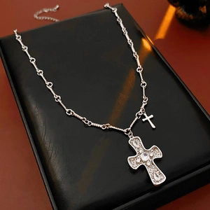 Close-up of double cross pendants with sparkling zircons on a textured silver chain