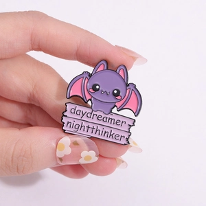 Cartoon purple bat enamel pin with daydreamer nightthinker text and pink wings
