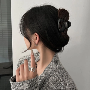 Side view of a woman wearing a minimalist black metal hair claw and silver earrings