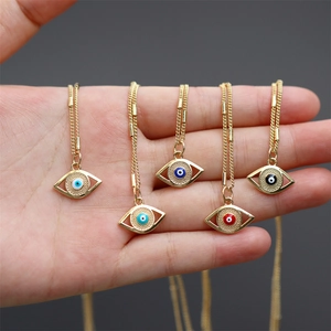 Detail of five colorful evil eye enamel pendants on gold chains held in a person's hand