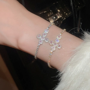 Macro detail of elegant zircon butterfly cross bracelet with pink stone on model wrist