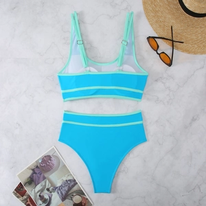 Flat lay of sky blue two-piece bikini set with mint green trim on marble background