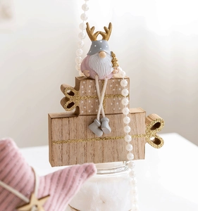Detail of pink Christmas gnome with antlers and wooden gift boxes in Nordic style