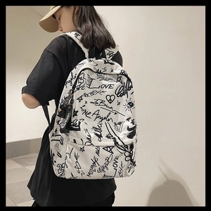 Side view of white canvas backpack featuring black graffiti print on a female model
