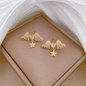 Macro detail of gold wing and star earrings with pavé crystals in a jewelry box