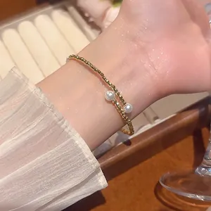 Elegant gold beaded bracelet with double white pearls on a model wrist in a soft setting