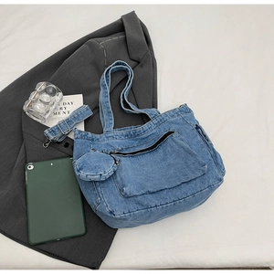 Flat lay of a denim tote bag with front pocket and a small round coin purse attachment