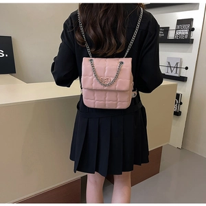 Pink quilted mini bag with heart hardware worn as a stylish backpack on a model