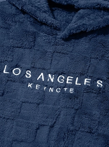 Macro view of Los Angeles Keynote lettering on warm navy blue sherpa fleece hoodie fabric