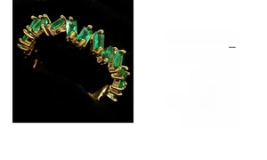 Macro shot of gold eternity ring with rectangular emerald stones in staggered prong setting
