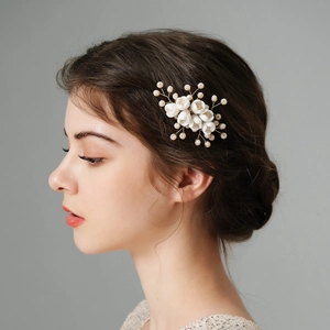 Elegant bridal hair comb with white ceramic flowers and pearls on a gold-plated wire frame