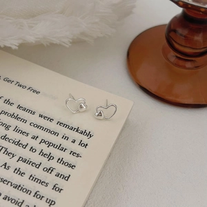 Detailed view of silver heart-shaped stud earrings on an open book page background