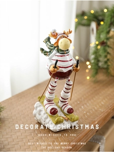 Detailed view of resin skiing reindeer ornament with red stripes and green scarf
