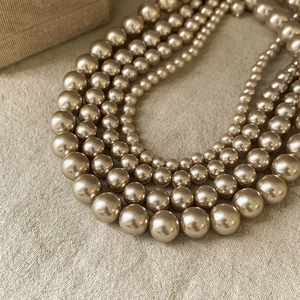 Vintage multilayer champagne pearl choker necklace on a beige textured fabric background