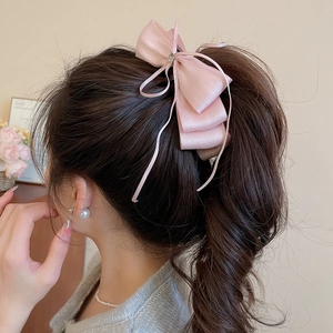 Detail of pink satin bow hair clip with sparkling rhinestones and long ribbons
