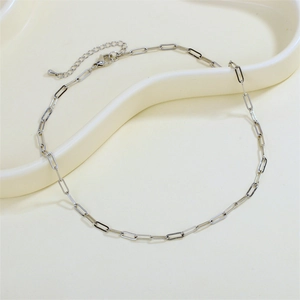 Close-up of a silver paperclip chain necklace with lobster clasp on a wavy tray