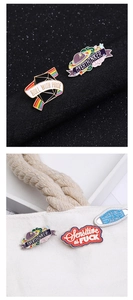 Detailopname van diverse emaille pins met Roll with Pride en Overthinker slogans