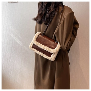 Brown leather shoulder bag with white faux fur trim and metal chain worn by a model