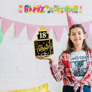 Caja de dinero para 18 cumpleaños en negro y dorado sostenida por una cumpleañera