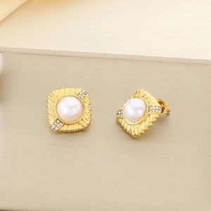 Gros plan sur des boucles d'oreilles vintage en or avec perle blanche et strass
