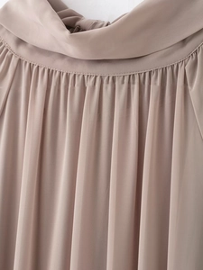 Détail du col plissé élégant sur une robe fluide en mousseline de couleur abricot
