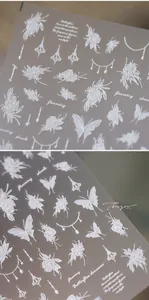 Macro detail of white embossed 3D nail art stickers featuring roses and butterflies