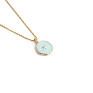 Detail of gold star pendant necklace with light blue enamel on white background