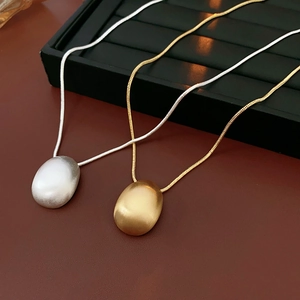 Détails des pendentifs ovales en métal brossé or et argent sur des chaînes serpent