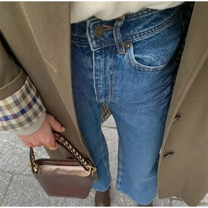 Nahaufnahme eines olivgrünen Wollmantels mit Jeans und brauner Leder-Eimertasche