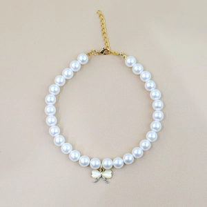 Detail of elegant pearl pet collar with a golden bow pendant and sparkling crystals
