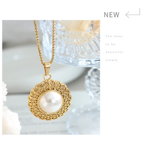 Detail of gold straw hat pendant with large white pearl and hollow lace craftsmanship