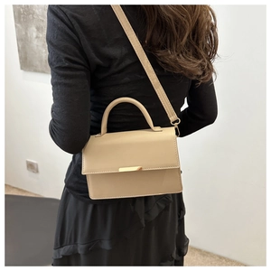 Fashionable beige small square handbag with gold hardware shown on a female model