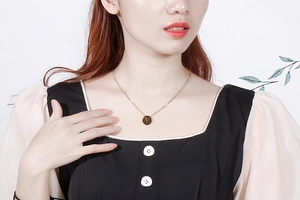 Close-up of golden letter V pendant necklace worn by a model with a clean aesthetic