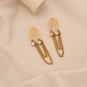 Macro detail of gold horseshoe earrings with white zircons and hanging tassel chains