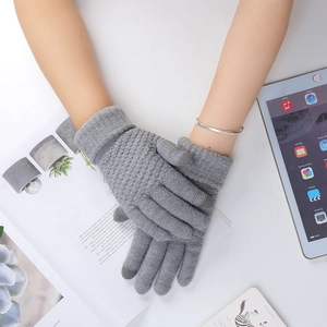 Close-up of gray knitted touchscreen gloves on a hand with casual lifestyle accessories