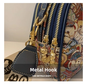 Close-up of golden bear-shaped zipper pullers and hardware hook on the woven bag
