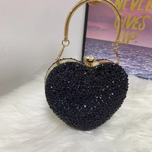 Detail of a heart-shaped evening bag featuring black beaded embroidery and gold handle