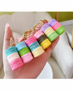 Detailansicht bunter Macaron-Kuchen-Schlüsselanhänger als Taschenanhänger in der Hand.