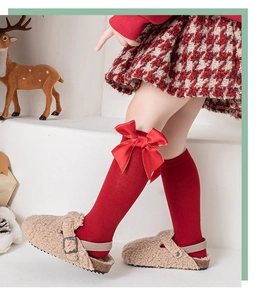 Détail de chaussettes hautes rouges pour filles avec un grand nœud en satin et style festif