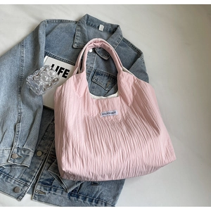 Detailaufnahme der rosa gesteppten Tragetasche mit Kiss Yourself Etikett auf Bett