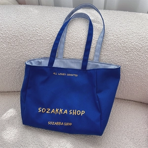Detailansicht der dunkelblauen Canvas-Tasche mit gelber Stickerei und gestreiftem Futter